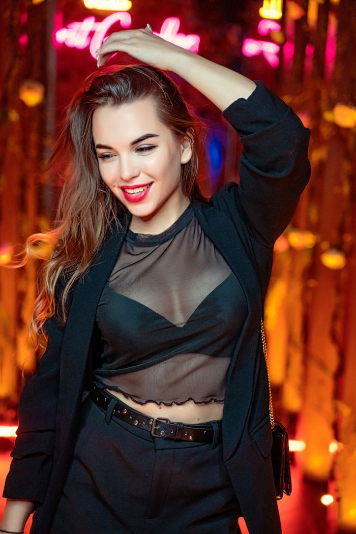 Stylish woman in sheer fabric top enjoying vibrant nightlife in Dubai.